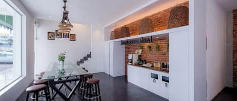 A modern kitchen with a glass dining table, bar stools, and a brick accent wall.
