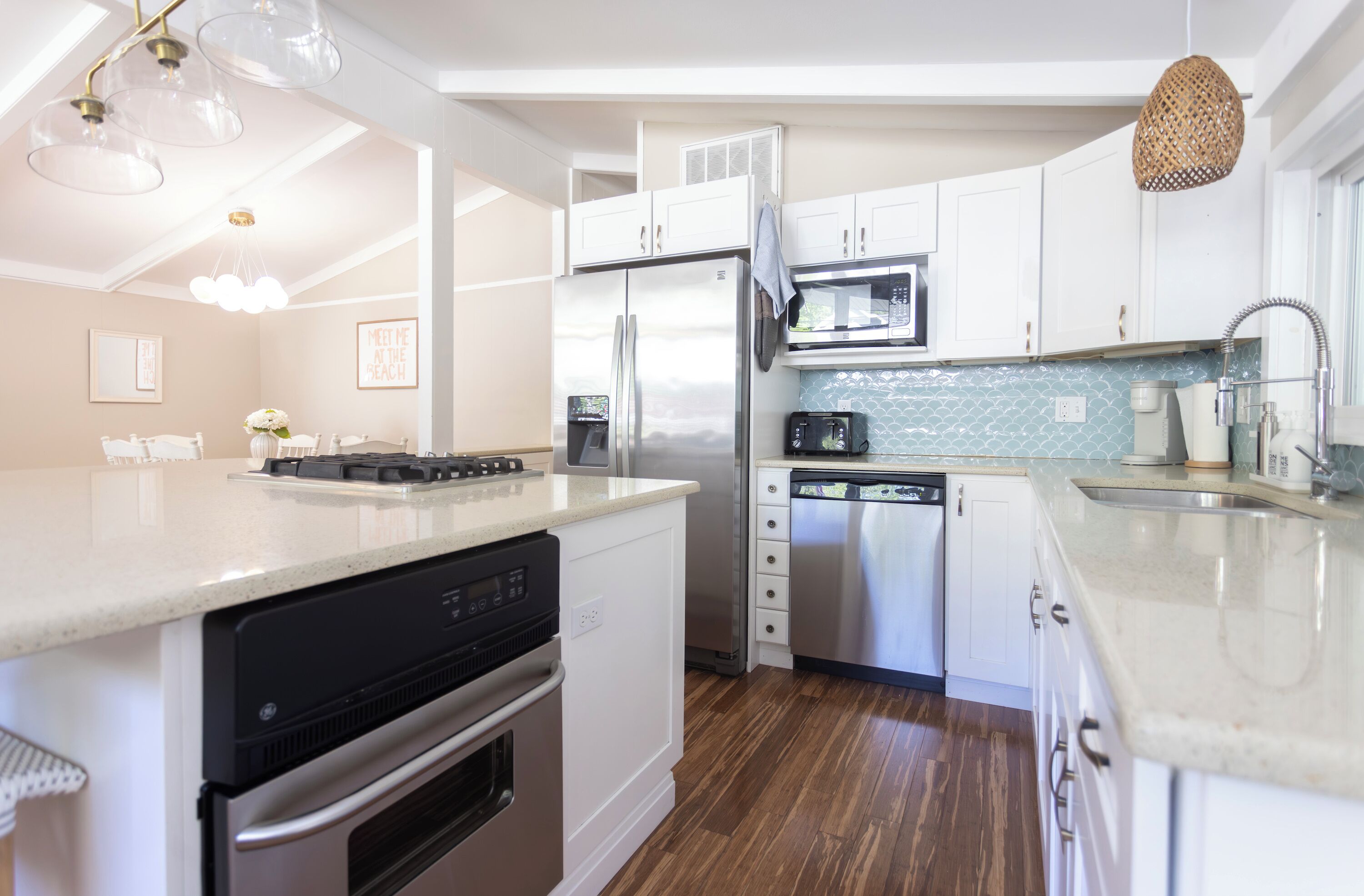 Una cocina moderna con armarios blancos, electrodomésticos de acero inoxidable y piso de madera.