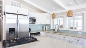 A modern kitchen with stainless steel appliances, white cabinets, and a large island. - 1000 FT From Lake Michigan, Hot Tub, Golf Cart (Grand Beach)