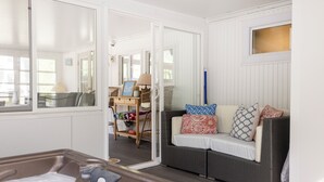 A cozy room with a wicker sofa, a small table with a lamp, and a view through a glass door. - 1000 FT From Lake Michigan, Hot Tub, Golf Cart (Grand Beach)