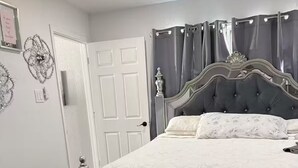 A bedroom with a large bed, a bedside table, a chandelier, and a door. - Serene 5-bedroom house with AC in vibrant Houston (Houston)