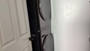 A laundry room with two stacked washers and dryers, a wooden floor, and white walls. - Serene 5-bedroom house with AC in vibrant Houston (Houston)