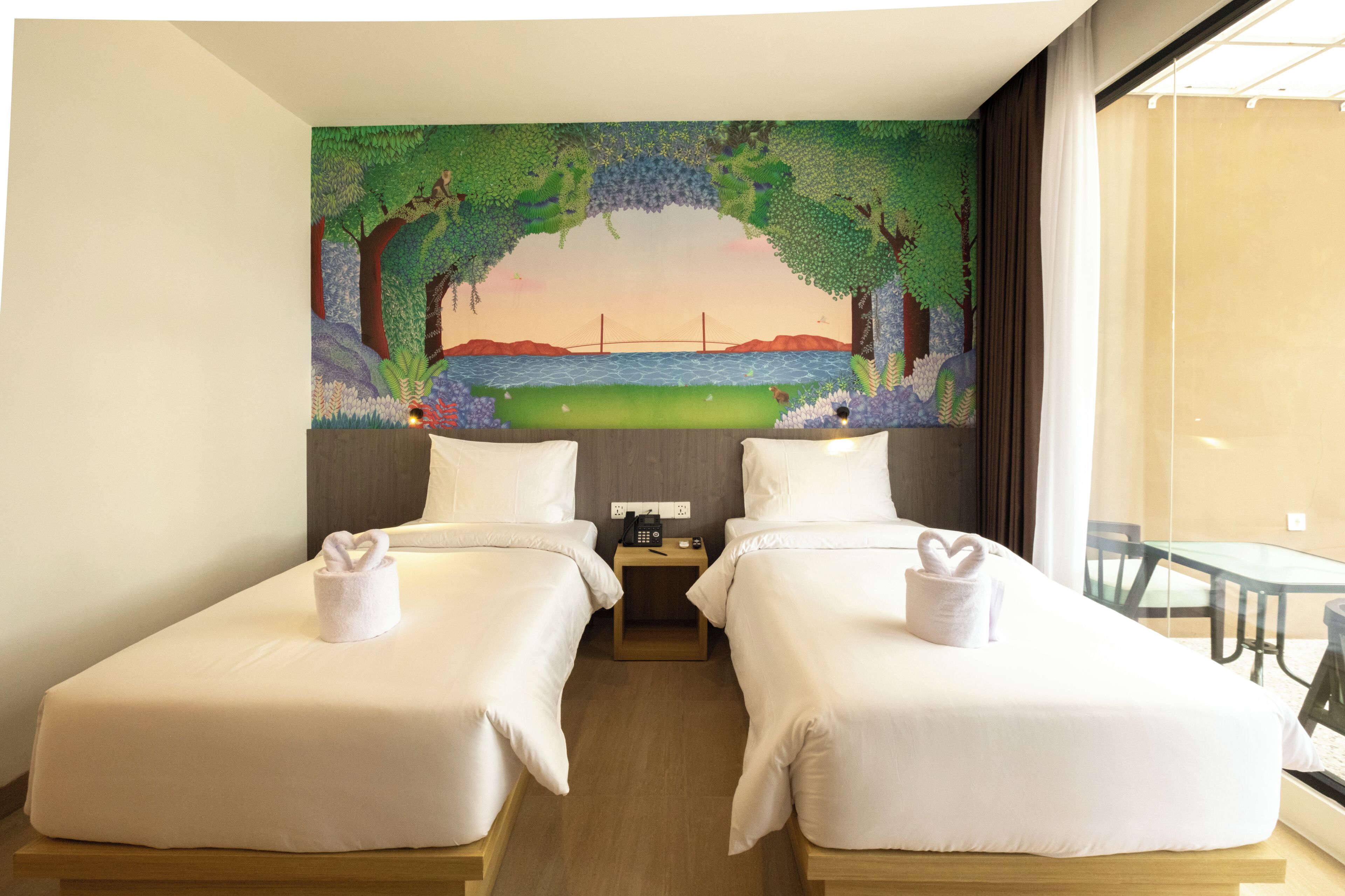 Habitación de hotel con dos camas, un mural de un paisaje y vista a un puente.