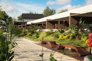 Un espace extérieur moderne doté d’une allée pavée, de bancs et d’une végétation luxuriante.