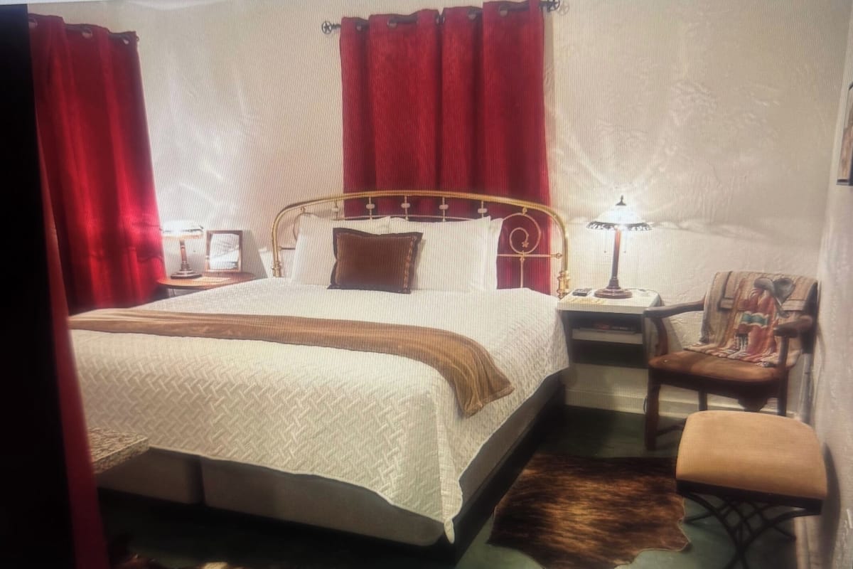 A neatly arranged bedroom with a bed, a chair, a nightstand, and a lamp.