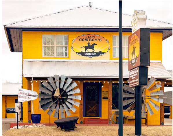 A yellow building with a large windmill and a sign reading "The Last Cowboy's Court."
