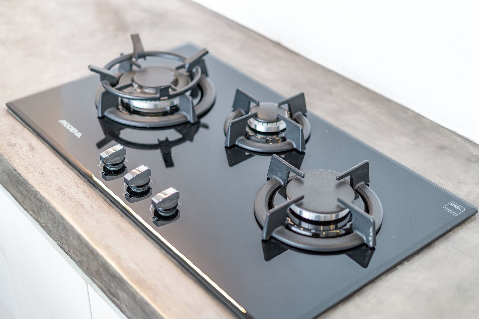 A black gas stove with four burners and four knobs on a kitchen countertop.