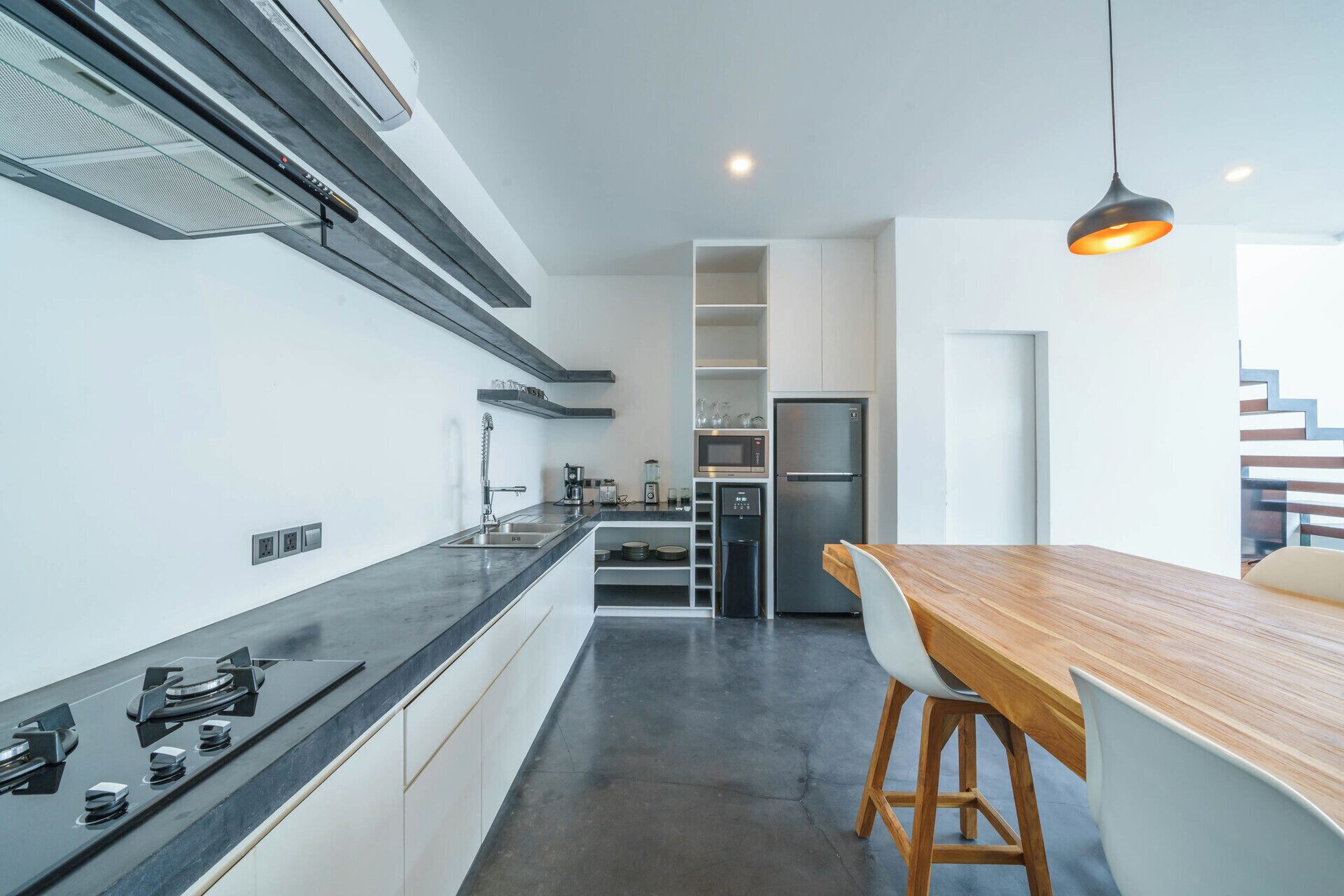 A modern kitchen with a central island, stainless steel appliances, and a hanging light fixture.