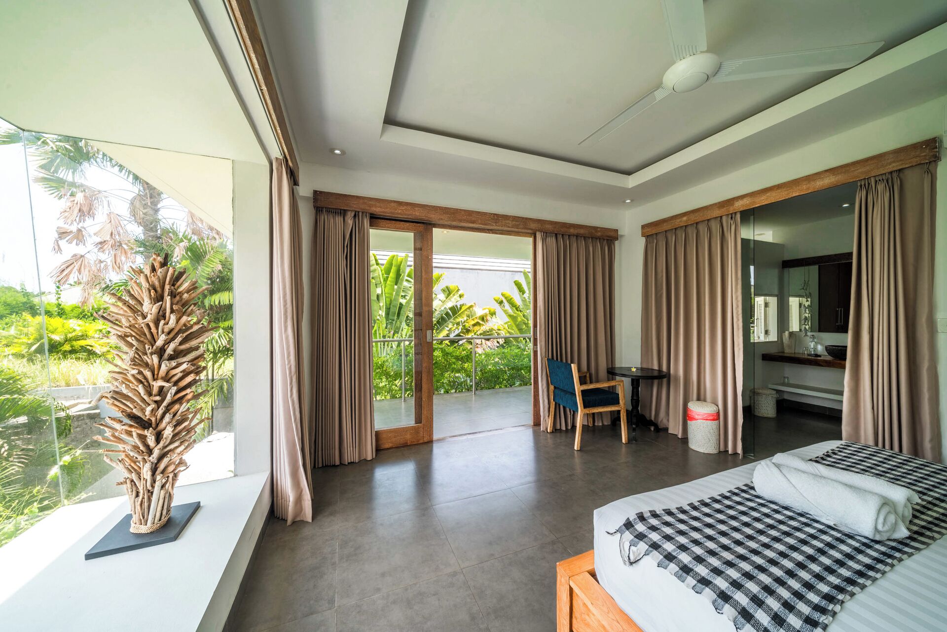 Une chambre d’hôtel moderne dotée d’un grand lit, d’un coin repas et d’un balcon avec des rideaux.