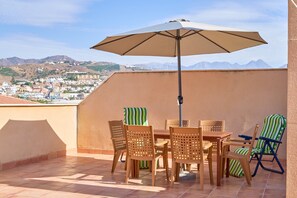 Une terrasse avec une table et des chaises, une serviette à rayures et un parasol.