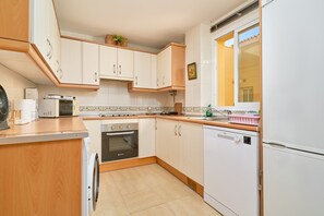 A compact kitchen with white cabinets, a built-in oven, a microwave, and a dishwasher.