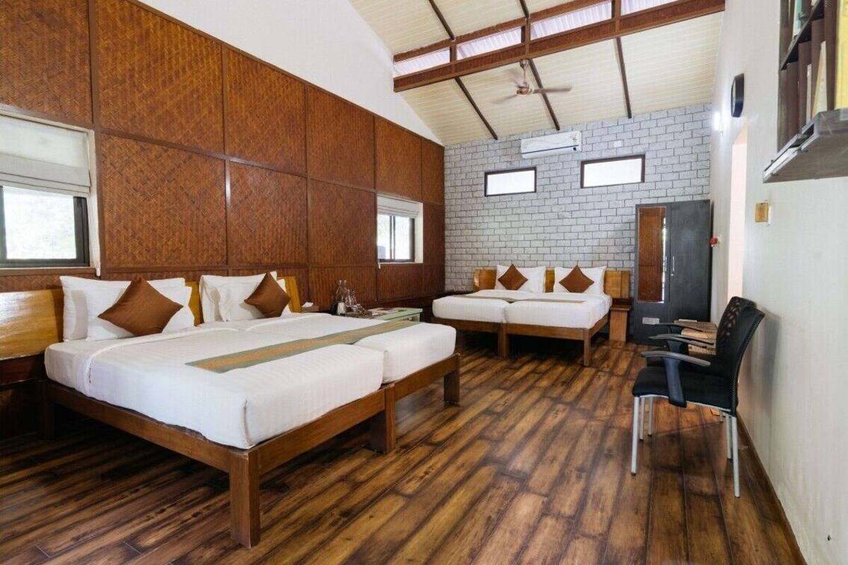 Une chambre d’hôtel avec deux lits, un plancher en bois, un mur en briques et un ventilateur de plafond.