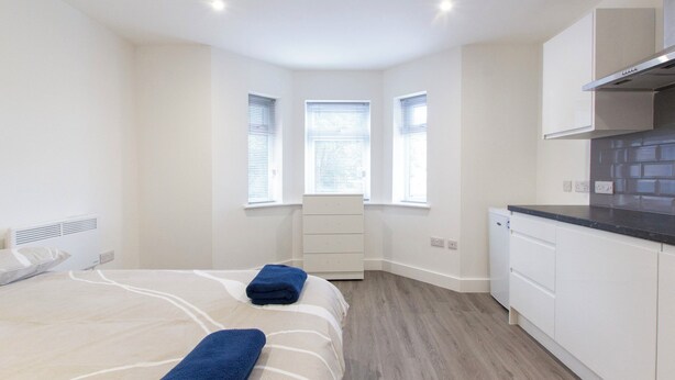 Un dormitorio moderno con cama, cómoda y ventana.