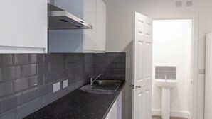 Una cocina moderna con armarios grises, encimera negra y salpicadero con azulejos grises.