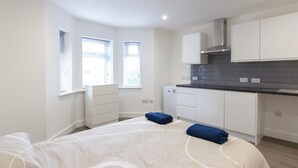 Un dormitorio moderno y funcional con cama y una kitchenette pequeña.