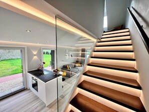 A modern interior with a staircase, a kitchen area, and a view of the outdoors. - LandGut & Residenz Driehof (Tecklenburg)