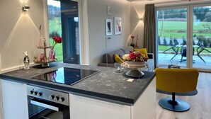 Una cucina moderna con piano cottura integrato, un'area pranzo con una sedia gialla e vista sull'esterno.