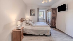 Une chambre à coucher avec un lit, une table de chevet, une lampe et un téléviseur fixé au mur.