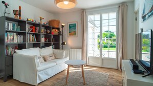 A modern living room with a white sofa, a bookshelf, a round coffee table, and a TV stand.