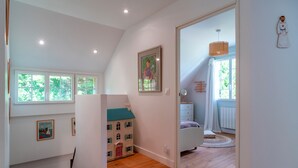 A bedroom with a bed, a dresser, a window, and a door leading to another room.