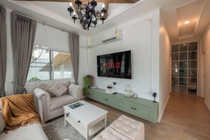 A modern living room with a sofa, coffee table, and a flat-screen TV mounted on the wall. - Springday House Pool Villa Near Nimman (Chiang Mai)