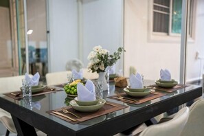 A dining table set with green plates, napkins, and cutlery, with a vase of flowers in the center. - Springday House Pool Villa Near Nimman (Chiang Mai)
