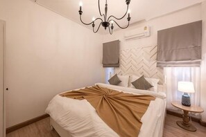 A hotel room with a bed, a chandelier, a round table with a lamp, and a window with curtains. - Springday House Pool Villa Near Nimman (Chiang Mai)