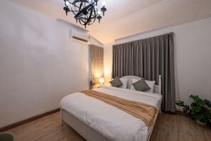 A bedroom with a bed, a chandelier, an air conditioning unit, curtains, and a potted plant. - Springday House Pool Villa Near Nimman (Chiang Mai)