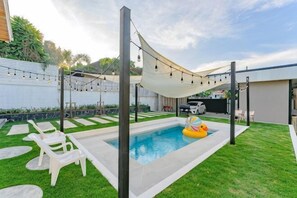 A backyard with a swimming pool, lounge chairs, a hammock, and string lights. - Springday House Pool Villa Near Nimman (Chiang Mai)