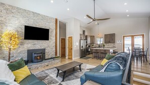 A modern living room with a fireplace, a sofa, a coffee table, and a TV mounted on a brick wall. - Family-Friendly Cabin Escape (Idaho Springs)