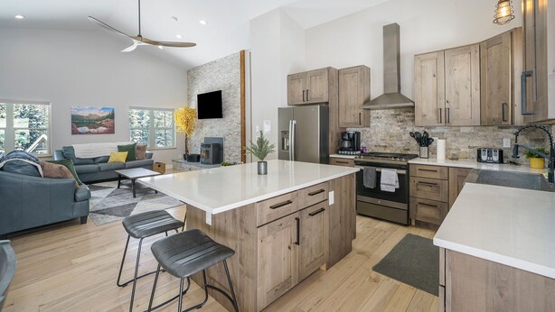 A modern kitchen with wooden cabinets, a large island, and a built-in stove. - Family-Friendly Cabin Escape (Idaho Springs)