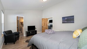 A bedroom with a bed, a TV, a chair, and a wooden door. - Family-Friendly Cabin Escape (Idaho Springs)