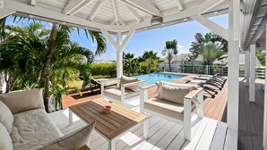 Un espace extérieur abrité comprenant une piscine, des chaises longues et une table.