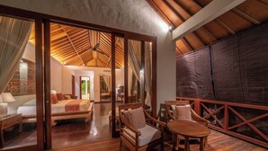A spacious room with a wooden floor, a bed with white linens, a wooden sofa, and a table. - The Complete Guide to Renting Your Exclusive Holiday Villa in Kabupaten Badung with Private Pool and Fully Staffed (Bali)