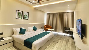 Una habitación de hotel moderna con una cama grande, un ventilador de techo, un televisor y un escritorio con una silla.