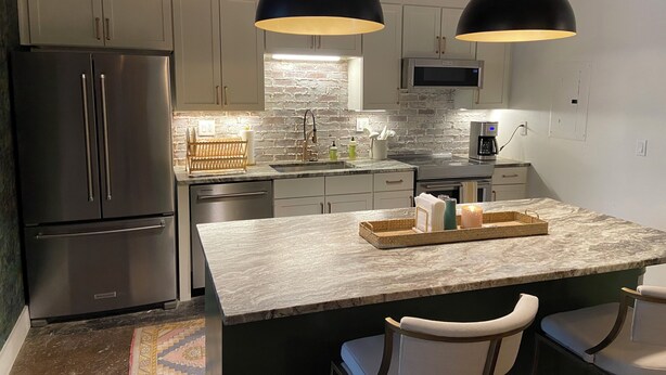A modern kitchen with a central island, stainless steel appliances, and pendant lighting.