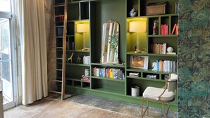 A room with a green bookshelf containing books, decorative items, and a ladder.