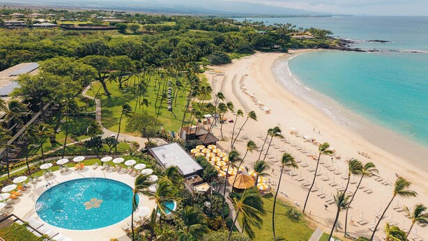 Resort tropical com piscina, praia e vista para o oceano.