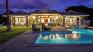 Uma casa de dois andares com piscina, área de estar externa e um pátio bem iluminado.