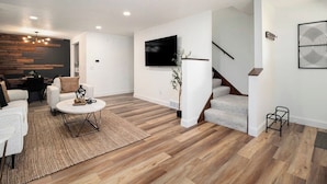 Uma sala de estar moderna com televisão de tela plana, uma escada e um espaço de jantar.