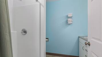 A bathroom with a white door, a blue wall, a towel rack with towels, and a white cabinet with drawers.