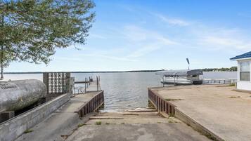 A concrete dock leading to a calm body of water with boats docked.
