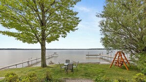 A lakeside view with a swing set, a table with chairs, and a dock extending into the water. - The Lakeview Motel (Lake City)