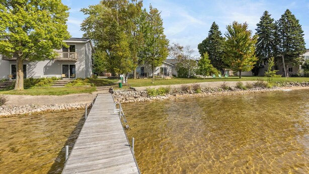 A wooden dock leading to a clear river, surrounded by residential buildings and trees. - The Lakeview Motel (Lake City)