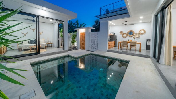 A modern house with a swimming pool, glass doors, and a dining area with a kitchen.