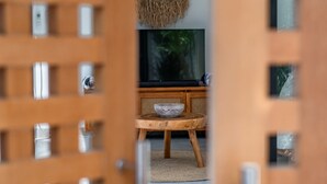 A room with a wooden door, a television on a wooden stand, and a woven basket on the stand.