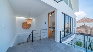 A modern staircase with a glass railing, leading to a balcony with a view of the cityscape.