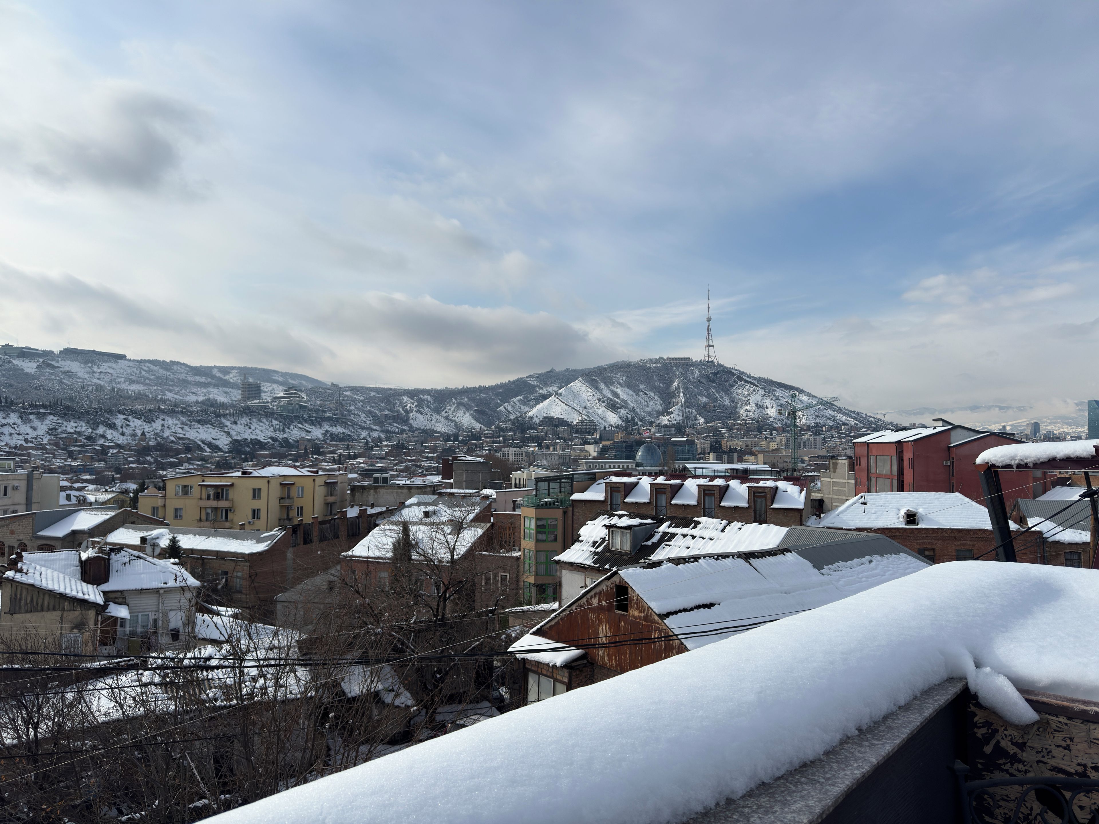 A cityscape with snow-covered buildings and a mountain in the background.