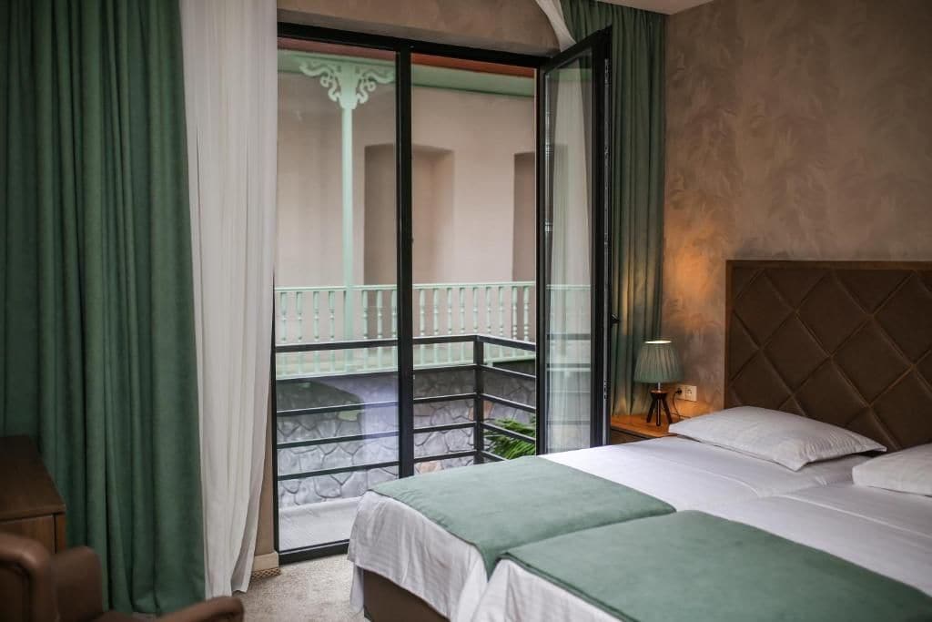 Ein Hotelzimmer mit Balkon, einem Bett, einem Nachttisch und einem Sessel.