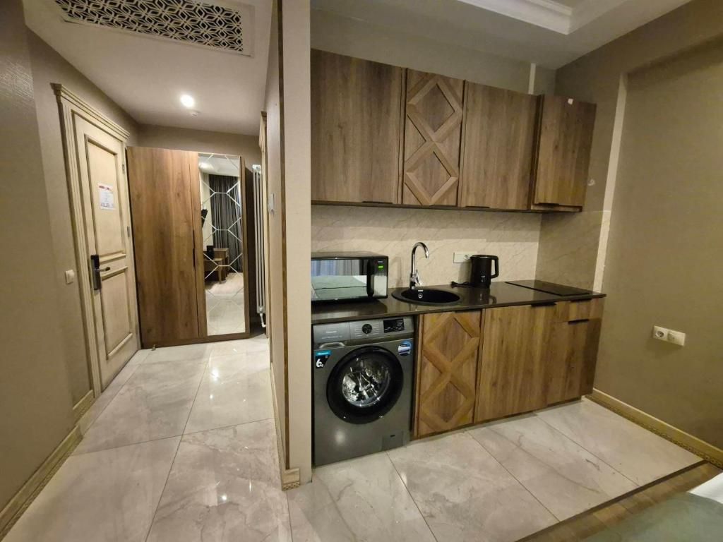 A compact kitchen with a washing machine, wooden cabinets, and a countertop with a coffee maker.